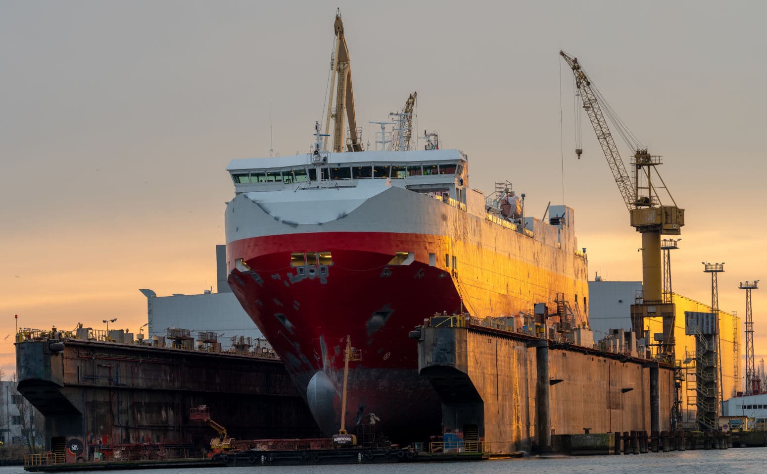 Large tanker in port with a crane on the dock.