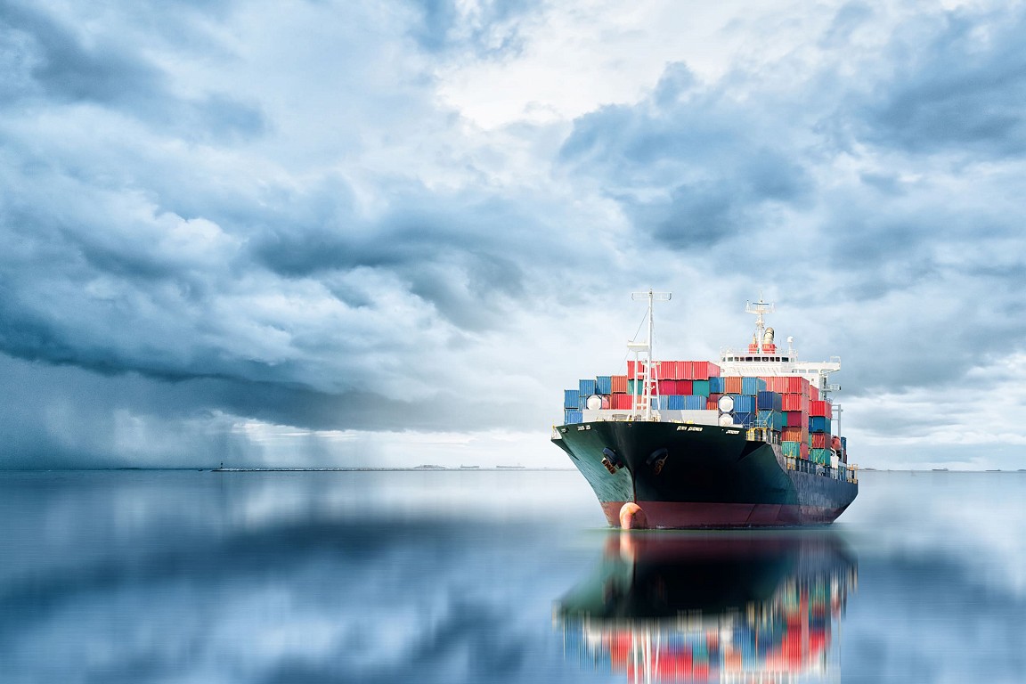 A container ship on the open ocean with dramatic skies.